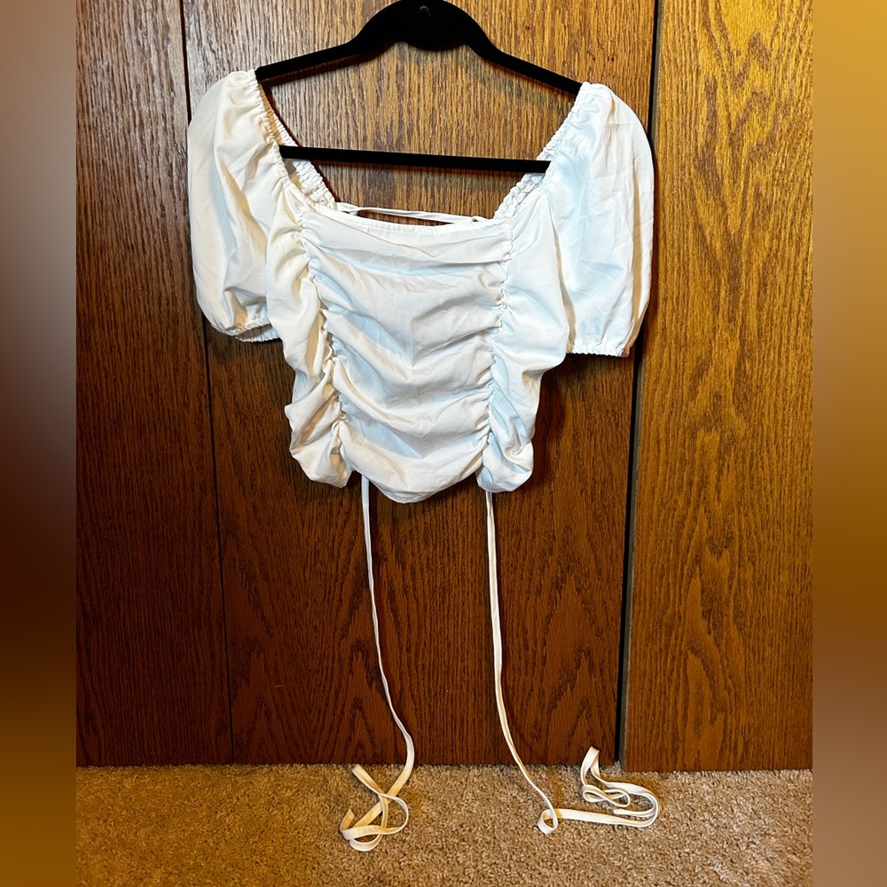 White ruffle tee shirt with open tie back. Size medium.